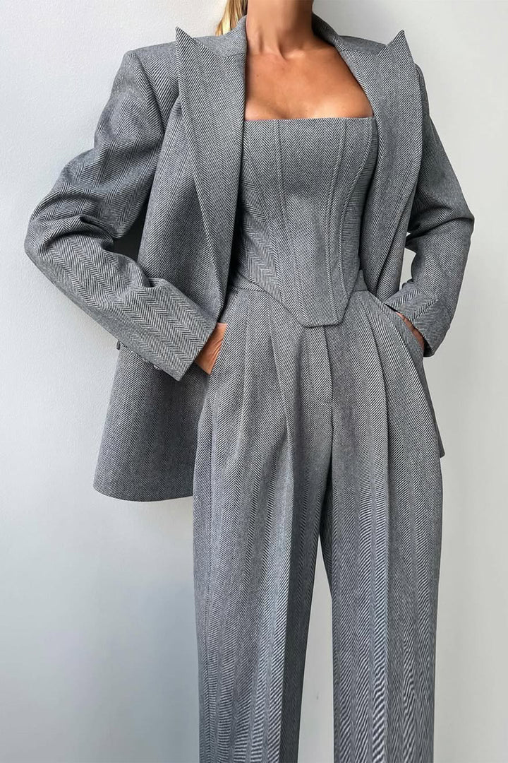 A woman wearing a double-breasted blazer with a matching top and trousers, all in a gray color.